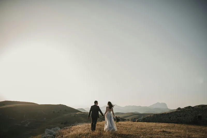 Pareja de novios caminando por una loma al atardecer