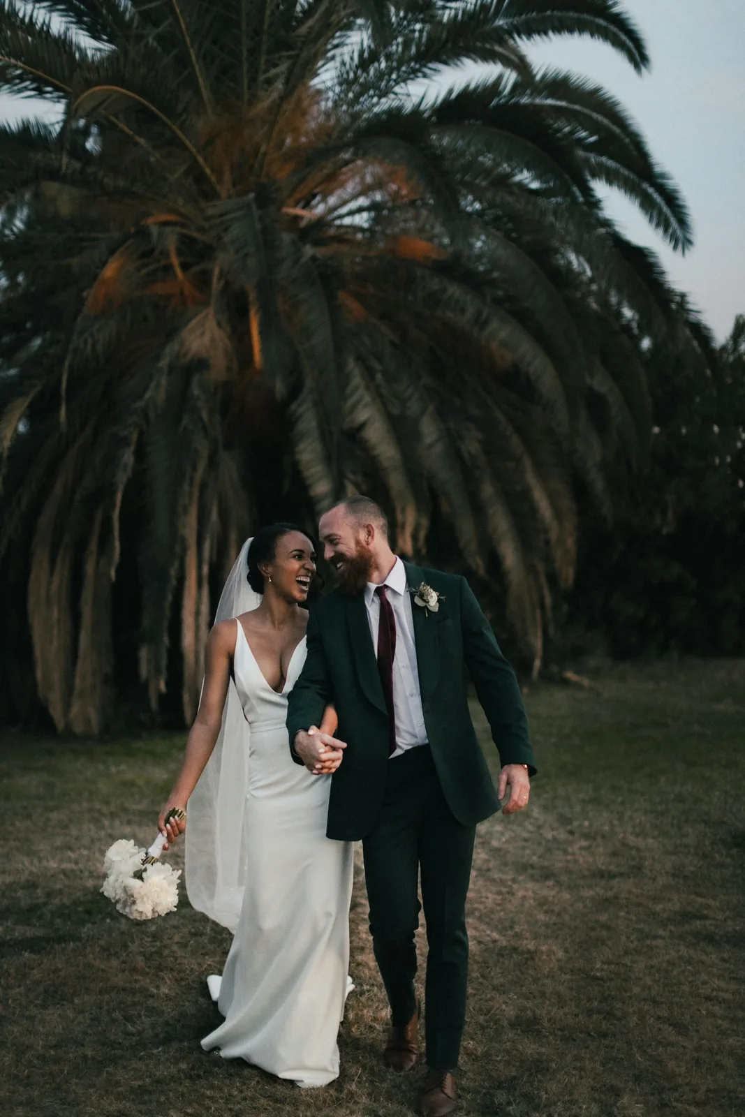 Novios caminando bajo una palmera