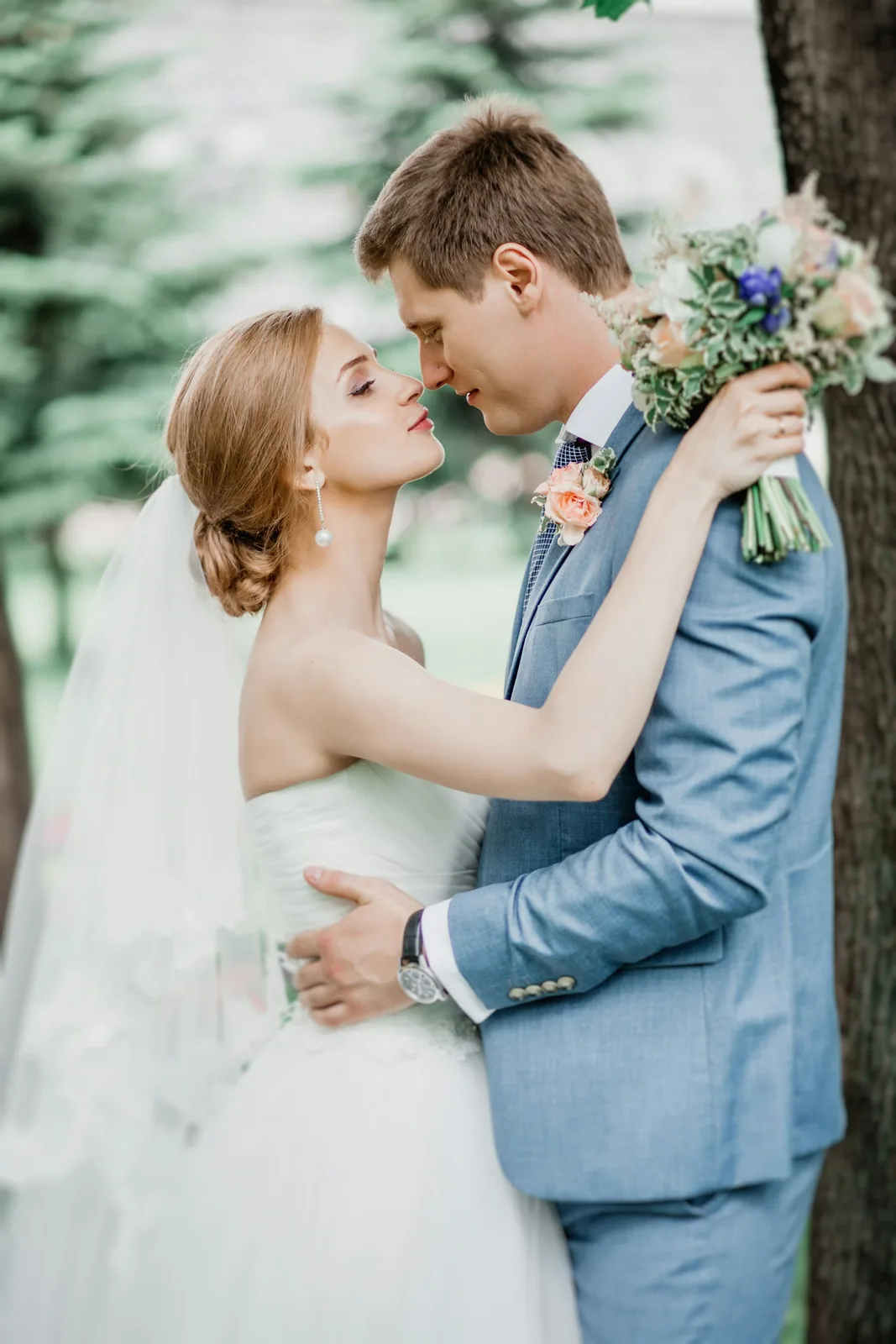 Novios abrazados frente a un árbol