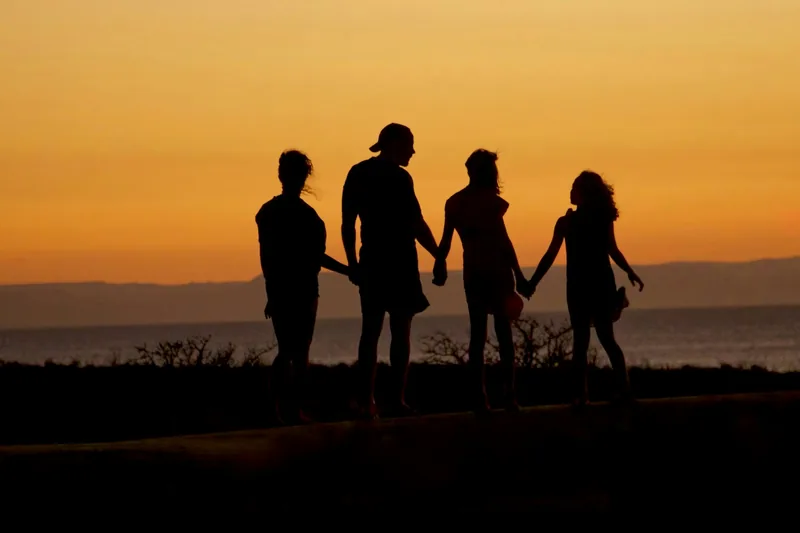 Familia de la mano frente al mar al atardecer