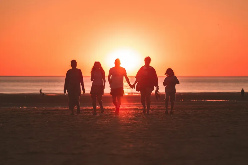 Familia caminando hacia el sol en la playa
